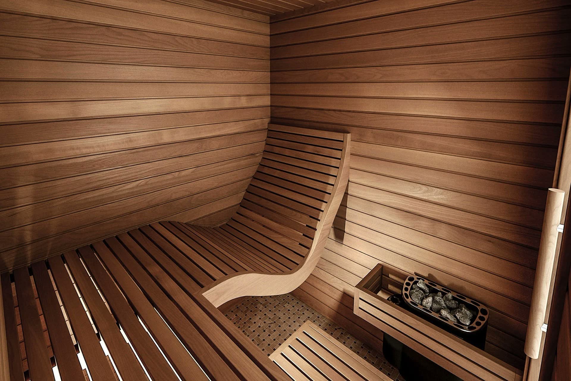 Sauna interior lined in warm brown wood with a curved lounger bench and a heater with stones
