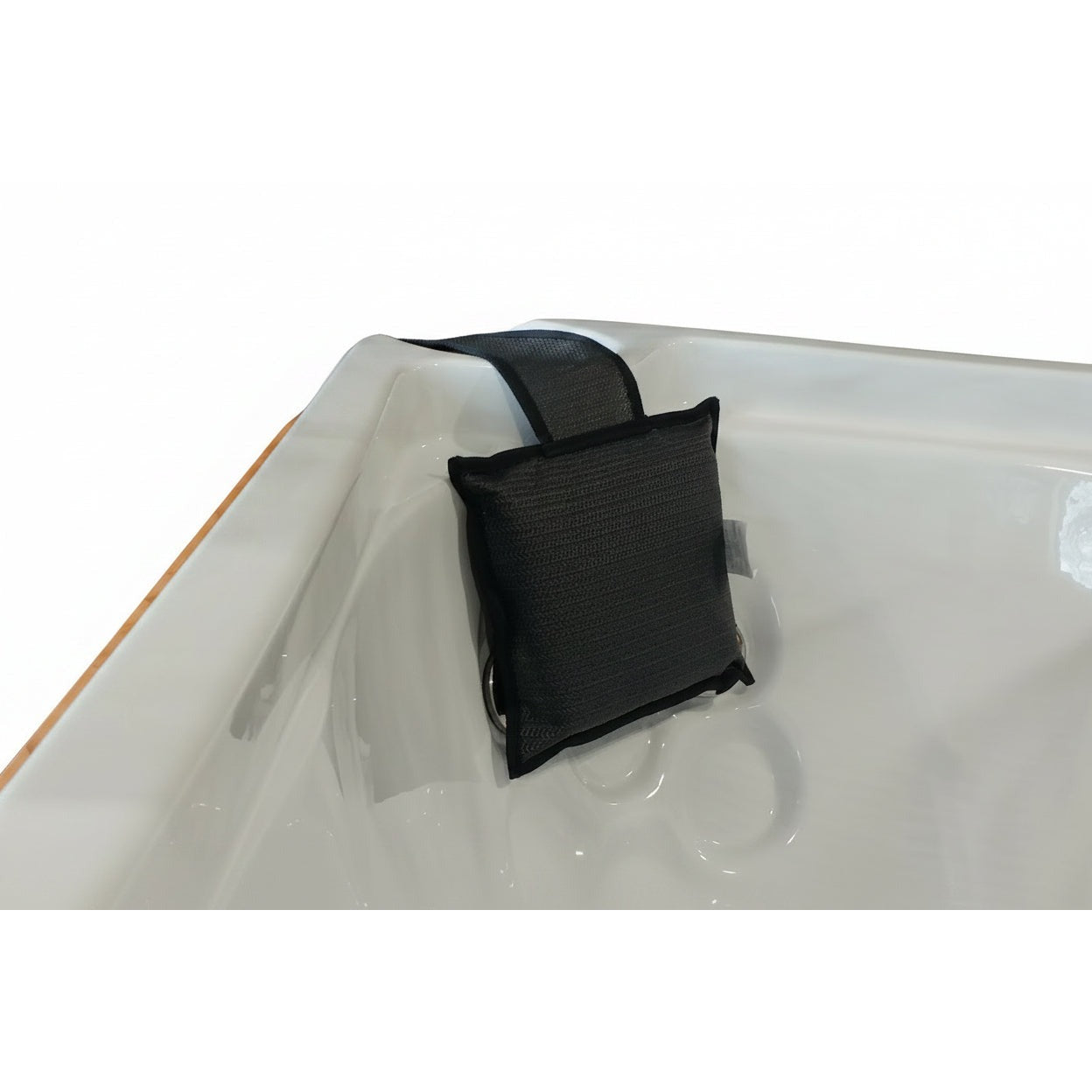 Black fabric weighted spa pillow draped over a white hot tub shell corner by its strap
